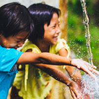 mosaic-initiative_200x200.png Two smiling children with hands in a stream of water